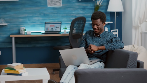 Hombre afroamericano agotado con exceso de trabajo sobrecargado que sufre de privación del sueño, quedándose dormido con la computadora portátil frente a él. retrato de autónomo cansado trabajando desde casa