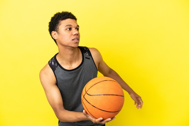 Hombre afroamericano aislado sobre fondo amarillo jugando baloncesto