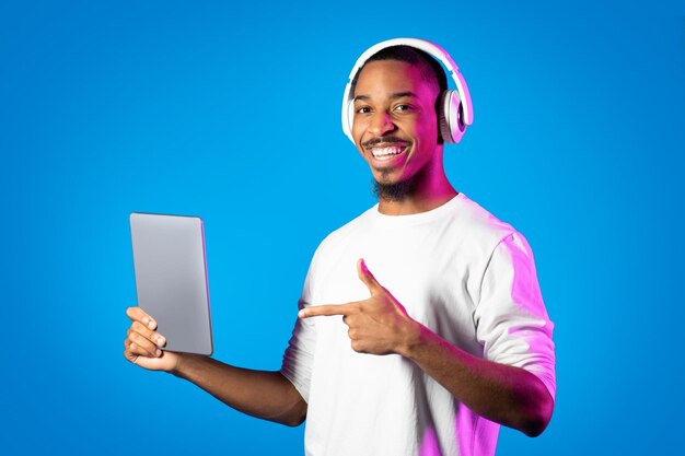 Hombre afroamericano alegre usando almohadilla digital y auriculares inalámbricos