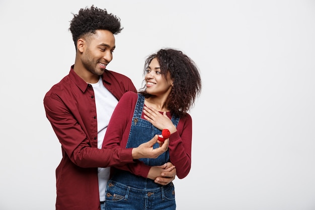 El hombre afroamericano apuesto joven sorprendentemente pregunta a su novia para la oferta.