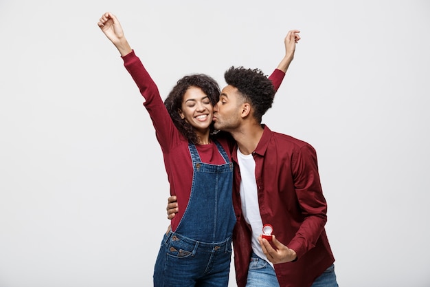 El hombre afroamericano apuesto joven sorprendentemente pregunta a su novia para la oferta.