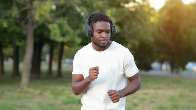 Hombre afroamericano en auriculares baila con música en el parque