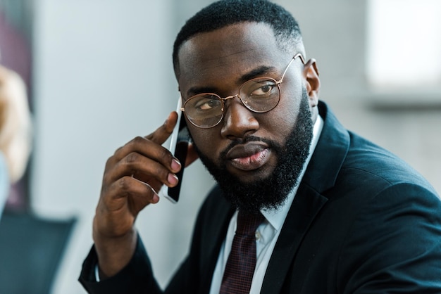 Hombre afroamericano barbudo y guapo hablando por teléfono inteligente