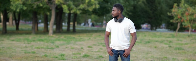 Hombre afroamericano camina en el parque de la ciudad verde en el césped