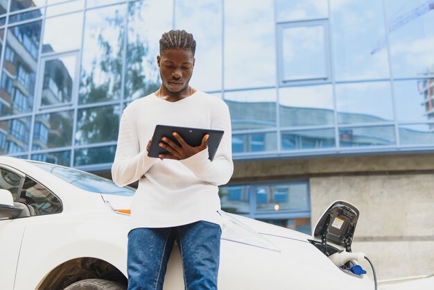 Hombre afroamericano cargando su coche eléctrico.