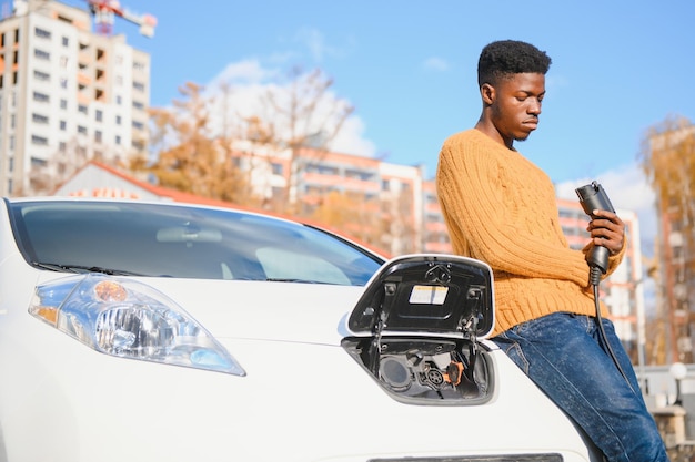 Hombre afroamericano cargando su coche eléctrico.