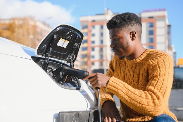 Hombre afroamericano cargando su coche eléctrico.