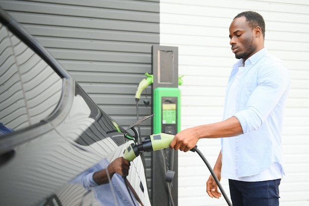 Hombre afroamericano cargando su coche eléctrico