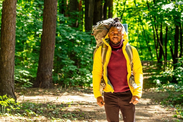 Hombre afroamericano con chaqueta amarilla con bolsa de oferta en los hombros en el bosque