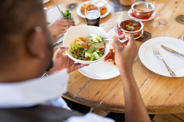 hombre afroamericano comiendo ensalada en un restaurante