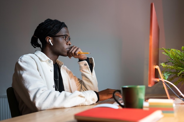 Un hombre afroamericano concentrado y exitoso usa una computadora en el lugar de trabajo con una taza de café