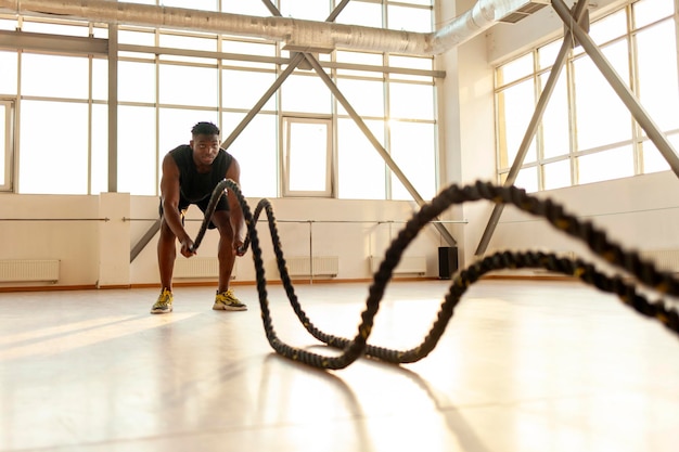 hombre afroamericano deportivo en ropa deportiva se entrena en el gimnasio por la mañana el tipo agita