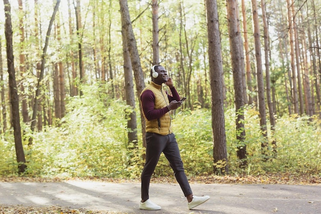 El hombre afroamericano escucha música en el espacio de copia del parque de primavera y el lugar para anunciar la aplicación Gadget y el concepto de servicio de transmisión