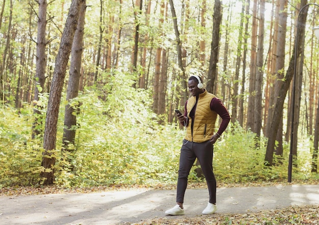 El hombre afroamericano escucha música en el espacio de copia del parque de primavera y el lugar para anunciar la aplicación Gadget y el concepto de servicio de transmisión