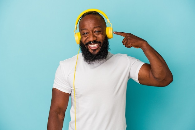 Hombre afroamericano escuchando música aislado sobre fondo azul.