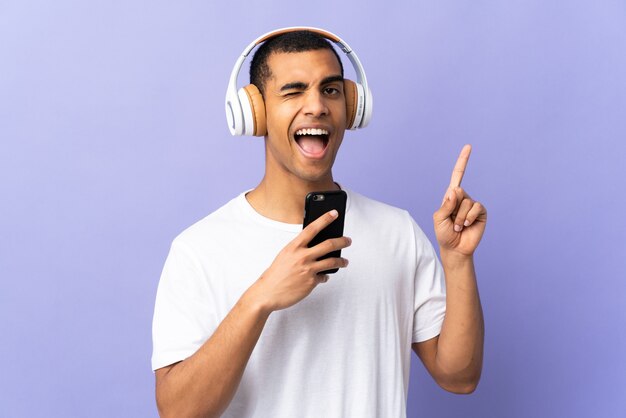 Hombre afroamericano en escuchar música púrpura aislada con un móvil y cantando