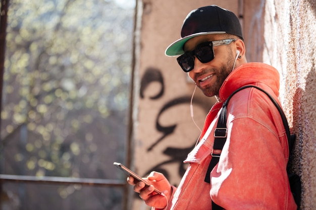 Hombre afroamericano con estilo feliz en gafas de sol escuchando música