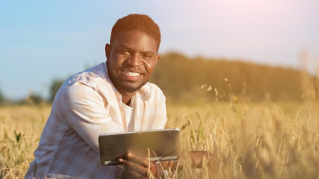 Hombre afroamericano explora enorme campo de trigo sonriendo