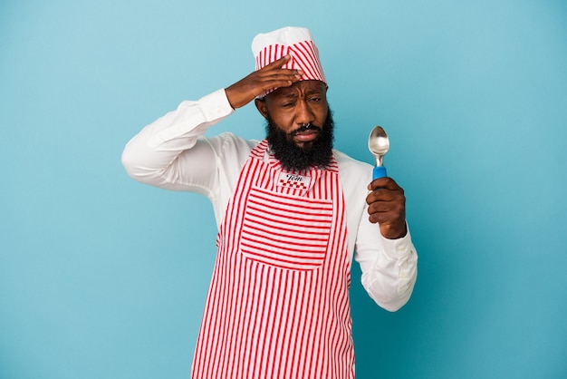 Hombre afroamericano fabricante de helados sosteniendo una bola de helado aislada sobre fondo azul sorprendido, ella ha recordado una reunión importante.