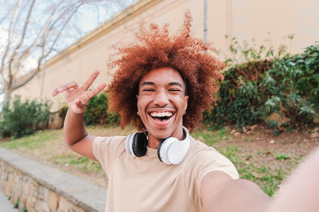 Foto hombre afroamericano feliz con cabello afro tomando un retrato de selfie un adolescente divirtiéndose y