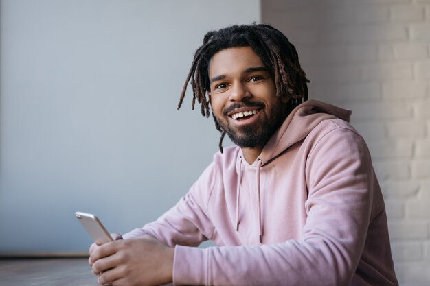 Hombre afroamericano feliz usando teléfono inteligente con aplicación móvil para pedir comida, compras en línea