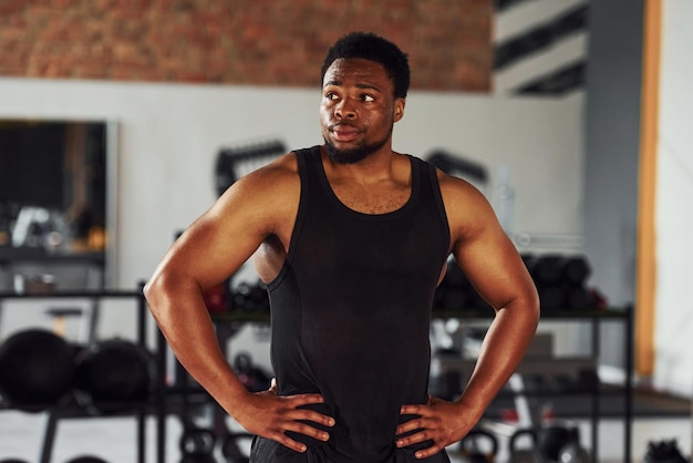 Hombre afroamericano fuerte con ropa deportiva de pie en el gimnasio