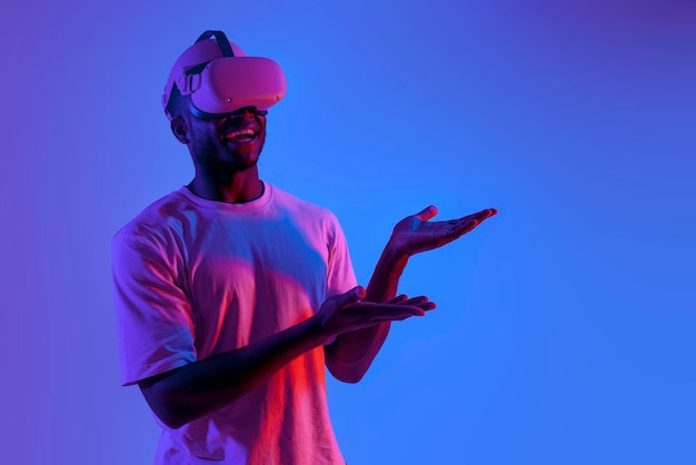 Hombre afroamericano con gafas de realidad virtual muestra sus manos a un lado en la iluminación de neón