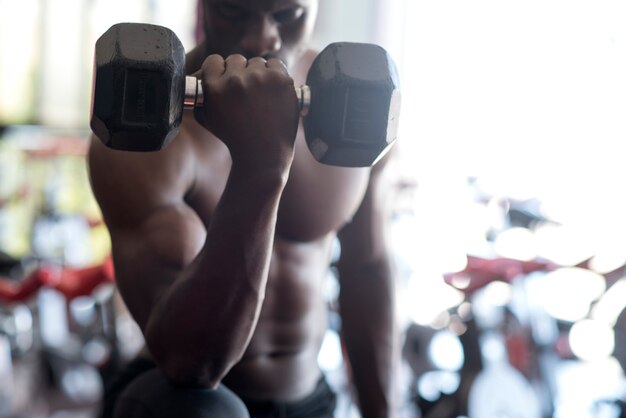 Foto hombre afroamericano haciendo ejercicios con mancuernas en un gimnasio