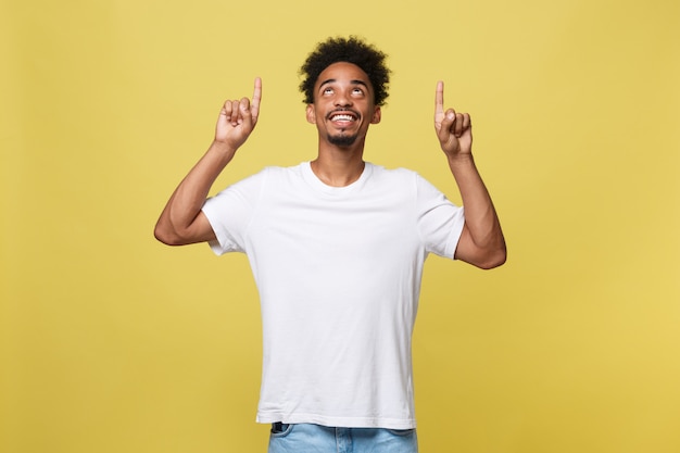 Hombre afroamericano hermoso joven sobre el fondo amarillo que señala hacia arriba.