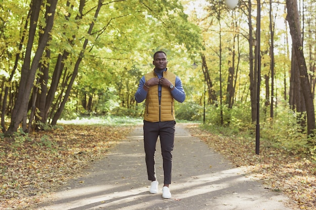 Hombre afroamericano hipster caminando en el parque otoño