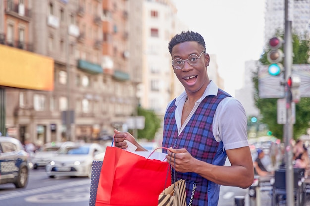 Hombre afroamericano joven que mira dentro del bolso de compras al aire libre