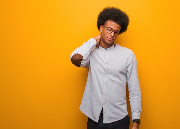 Hombre afroamericano joven sobre una pared anaranjada que sufre dolor de cuello