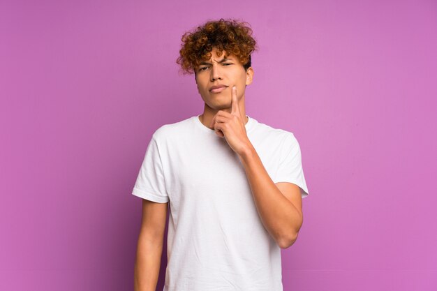 Hombre afroamericano joven sobre la pared púrpura aislada que mira el frente