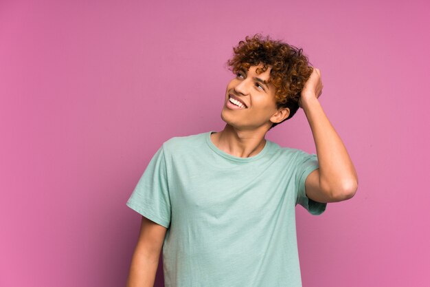 Hombre afroamericano joven sobre la risa púrpura aislada de la pared