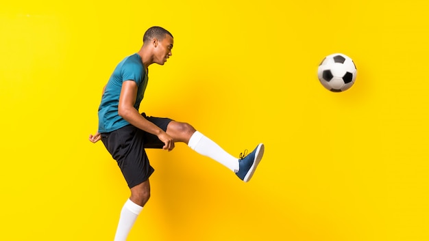 Hombre afroamericano del jugador de fútbol sobre fondo amarillo aislado