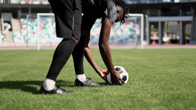 Foto hombre afroamericano jugando al fútbol en el campo del estadio un hombre corre con una pelota de fútbol por el campo