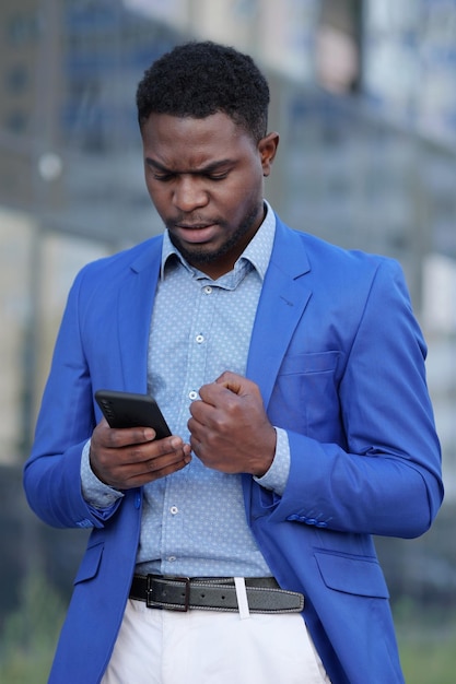 Hombre afroamericano mira el teléfono con expresión enojada