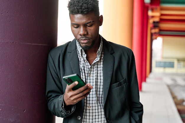 Hombre afroamericano mirando su teléfono inteligente con traje