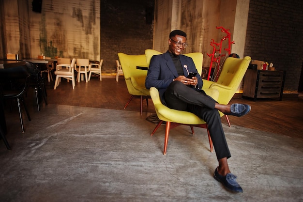 Hombre afroamericano de moda con traje y gafas posado en el café