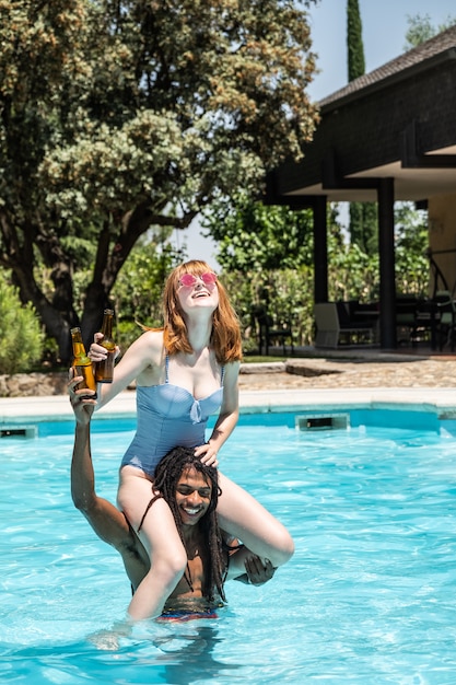 Hombre afroamericano y mujer blanca jugando en una piscina.