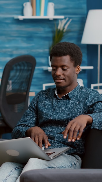 Hombre afroamericano navegando con ordenador portátil buscando redes sociales