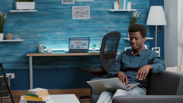 Hombre afroamericano navegando con ordenador portátil buscando redes sociales