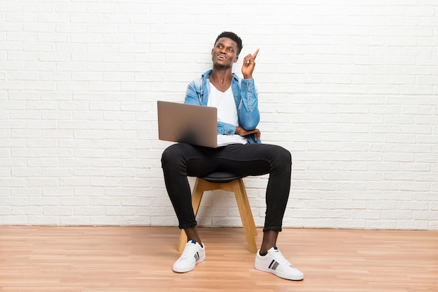 Hombre afroamericano que trabaja con su computadora portátil señalando con el dedo índice una gran idea