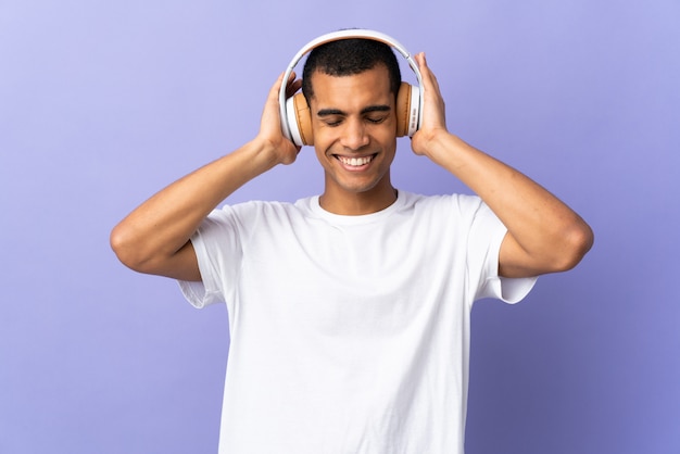 Hombre afroamericano sobre música de pared púrpura aislado escuchando