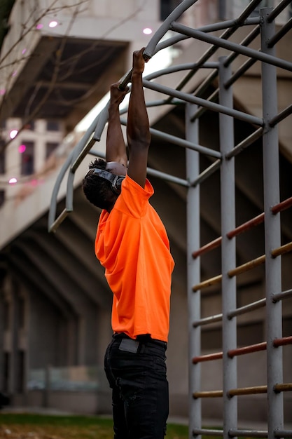 Hombre afroamericano tirando de sí mismo en barras horizontales