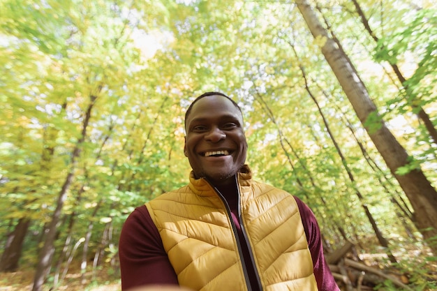 Hombre afroamericano tomando un autorretrato con un teléfono inteligente en el espacio de copia del parque de otoño Temporada de gente feliz y nuevo concepto de normalidad