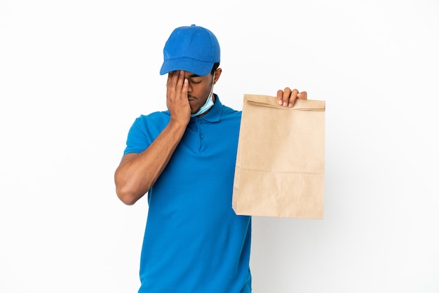 Hombre afroamericano tomando una bolsa de comida para llevar aislado sobre fondo blanco con expresión cansada y enferma