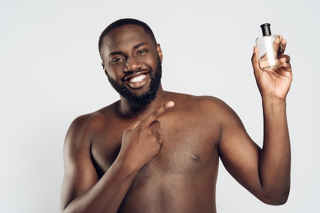 El hombre afroamericano usa loción para después del afeitado. Higiene masculina.