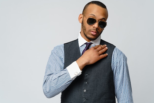 Hombre afroamericano vistiendo camisa y corbata sobre pared gris