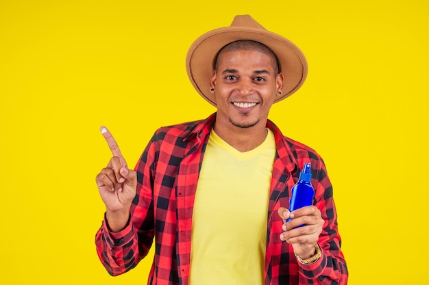 Hombre afrobrasileño eligiendo botella spf en estudio pared amarilla